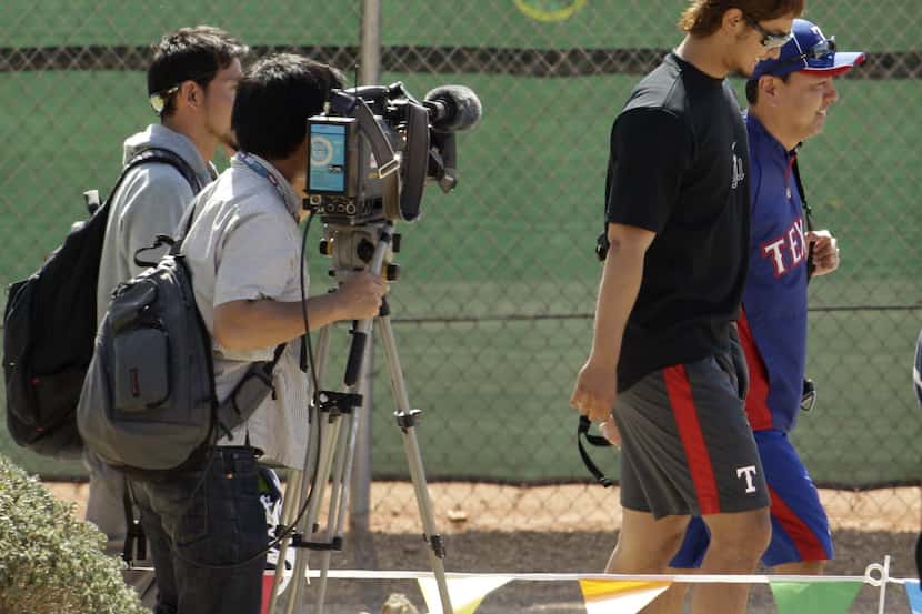 Texas Rangers pitcher Yu Darvish, second from right, from Japan, walks past a group of media...