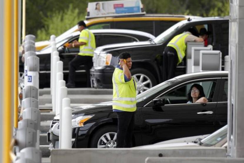 Workers at the south exit toll plaza help motorists at Dallas/Fort Worth International...