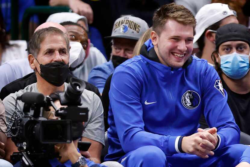 Dallas Mavericks guard Luka Doncic watches the second half from the bench with owner Mark...
