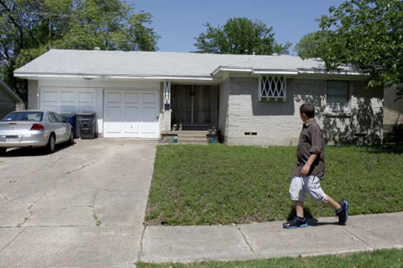 Thomas Savage, who lives in the neighborhood, walks past  the home of Aaron Ramsey and...