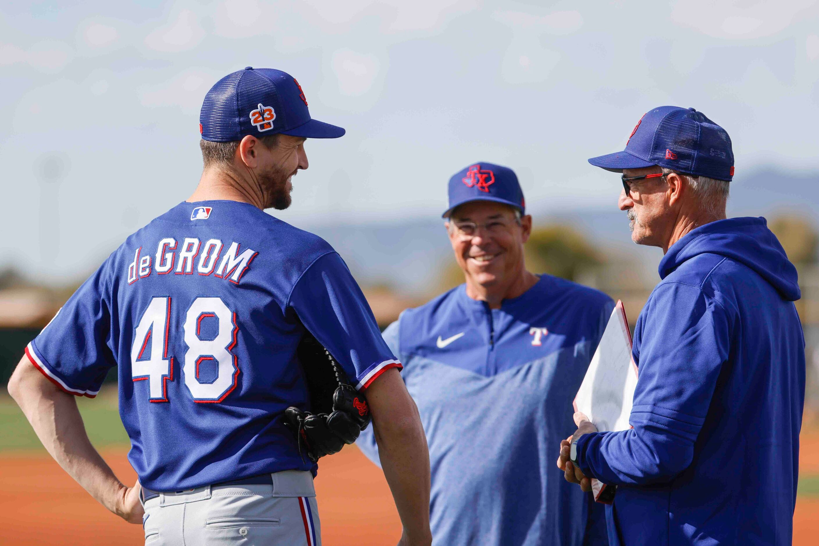 Texas Rangers pitcher Jacob deGrom, left, talks to special assistant Greg Maddux, center,...