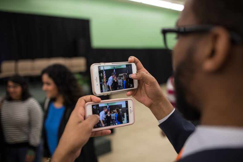 Dexter McCoy holds two cellphones as he takes pictures of Rep. Beto O'Rourke with supporters...