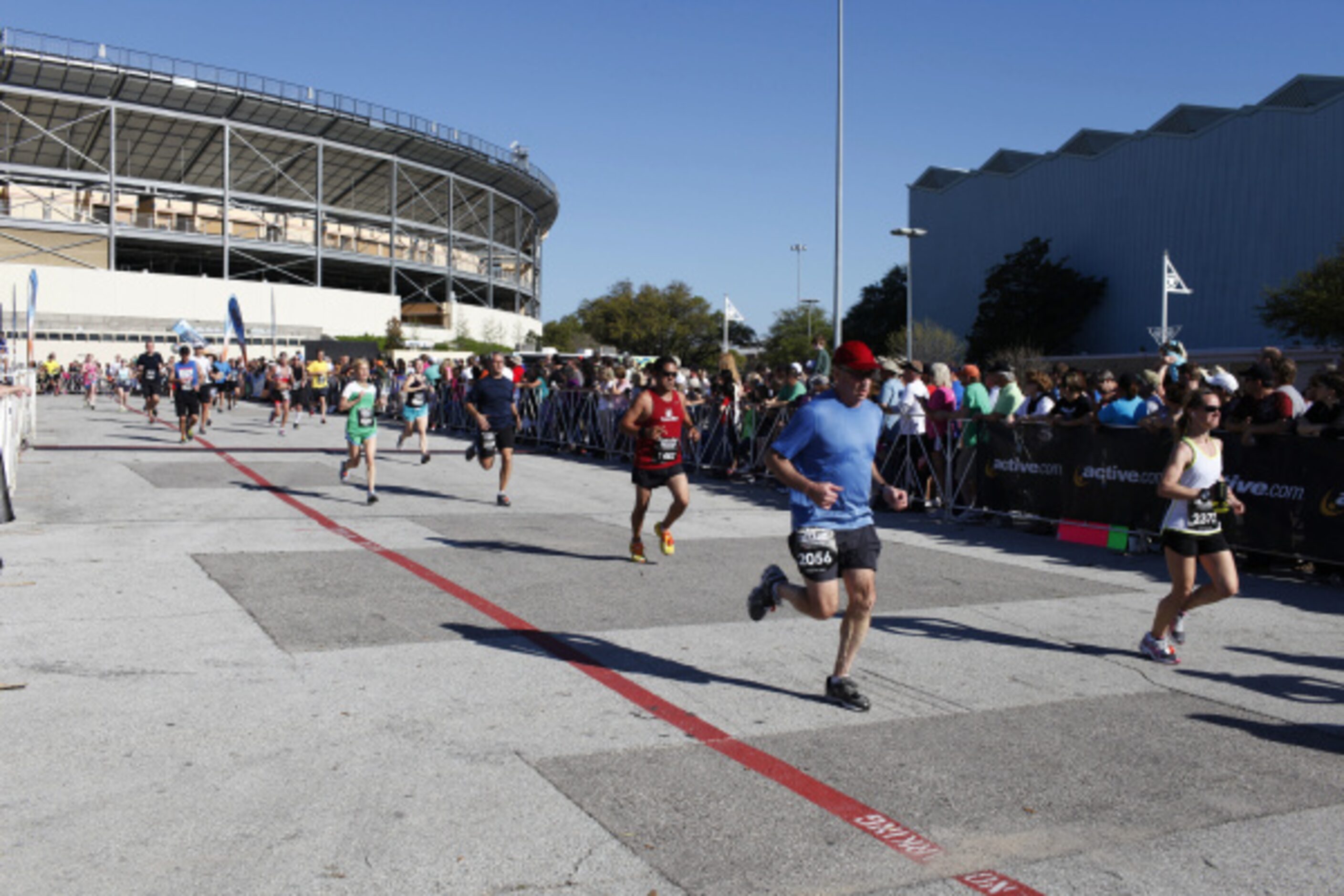 Running participants make their way into Fair Park past the Dallas Cowboy cheerleaders...