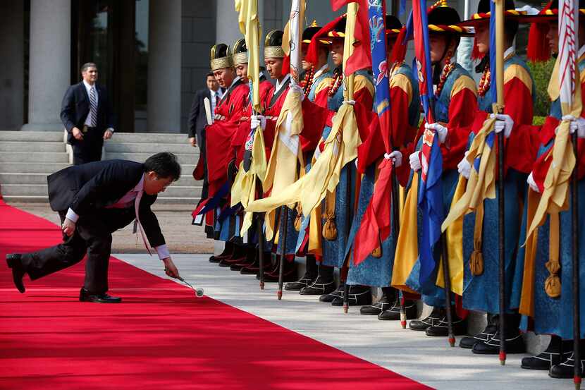  An aide uses a roller to pick up bits of lint and dust on the red carpet as Honor guard...