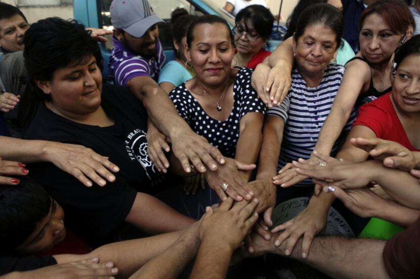 Tenants put their hands together in solidarity during a meeting Friday at the Dallas West...