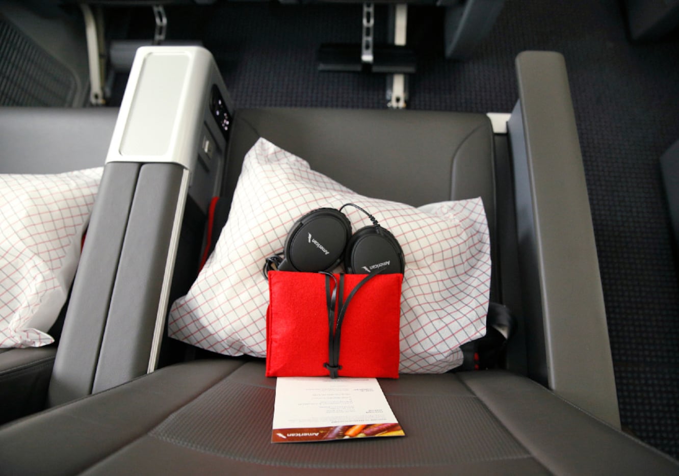 Headphones with a blanket and pillow are offered in American's premium economy cabin seating.