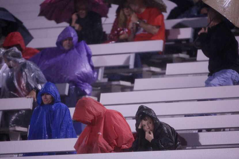 McKinney Boyd fans sit in the rain during a high school football game between Hebron and...