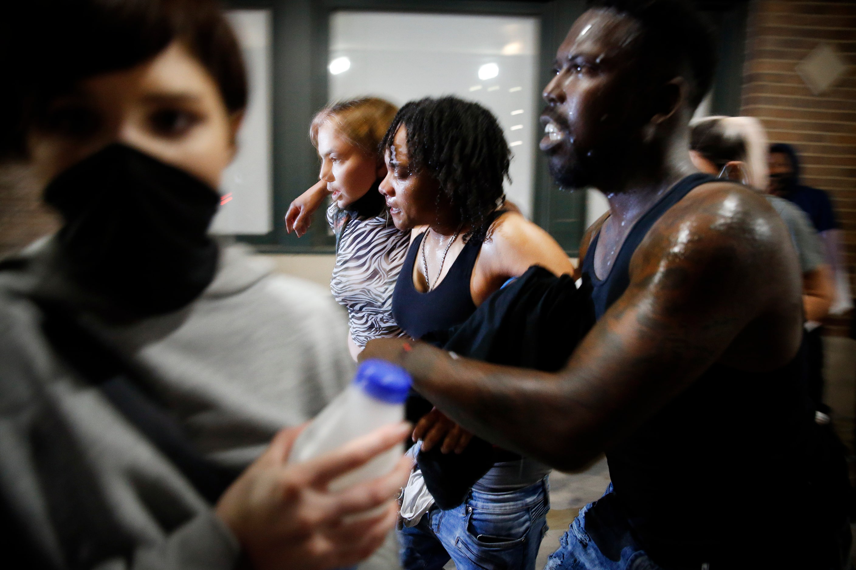 A female protestor (center) is helped to her feet after she was hit by a projectile as they...