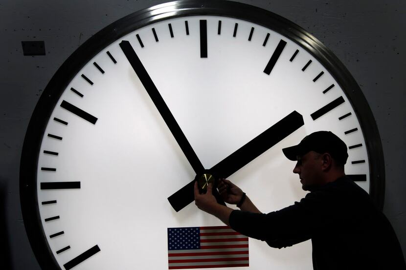  FILE - Dave LeMote uses an allen wrench to adjust hands on a stainless steel tower clock at...