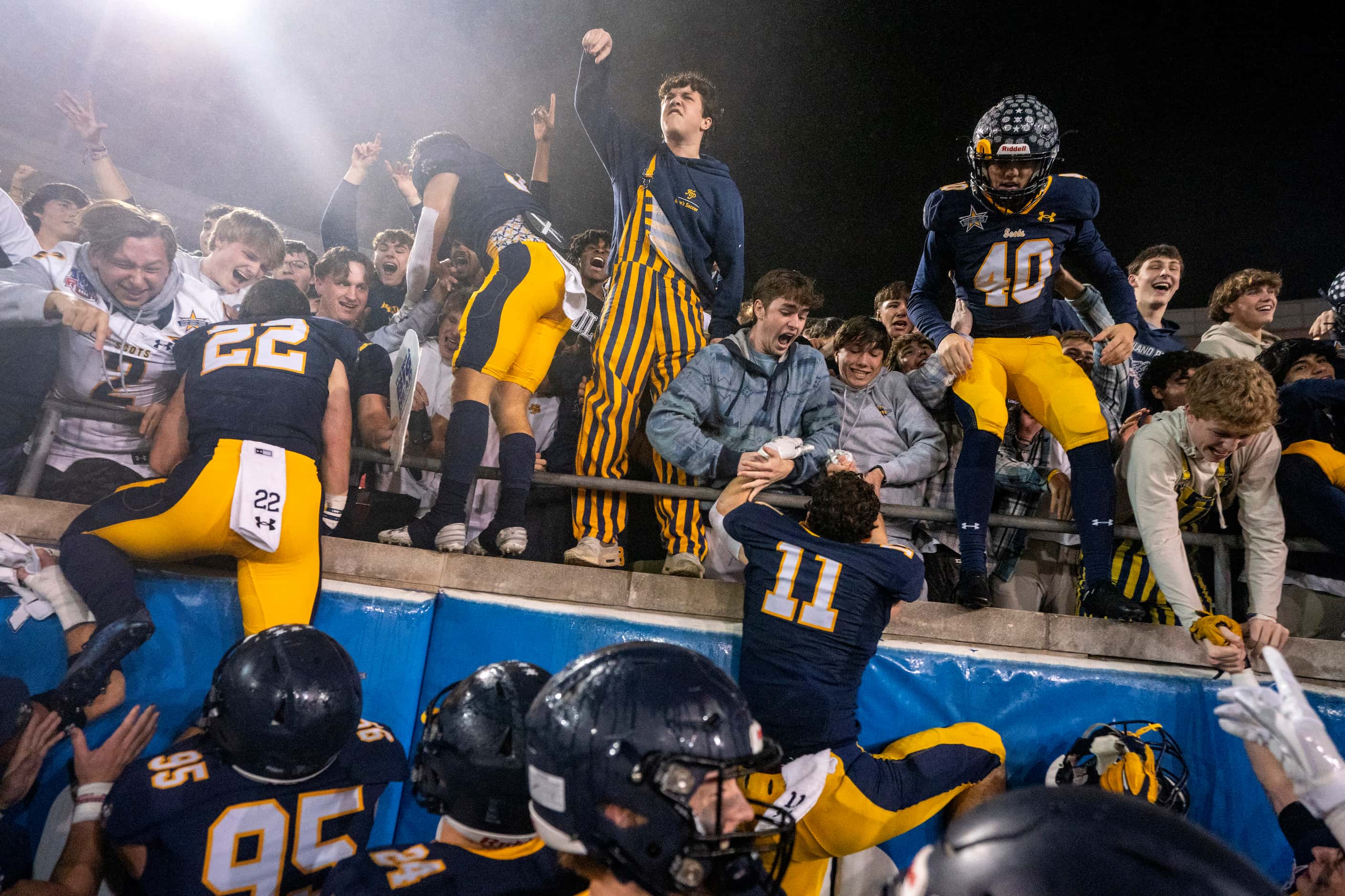 Highland Park players climb into the student section after beating McKinney 22-21 on a...