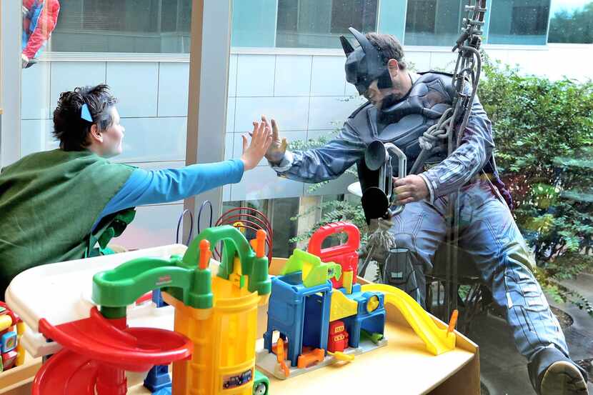 Children's Medical Center Plano patient Ryan Olin, left, reaches out to window washer Joshua...
