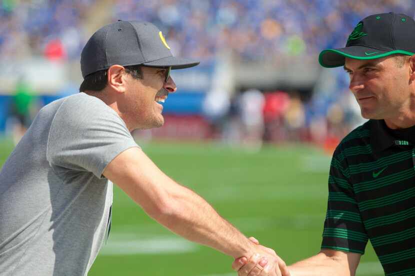 Actor Ty Burrell, left, shakes hands with Oregon coach Mark Helfrich before an NCAA college...