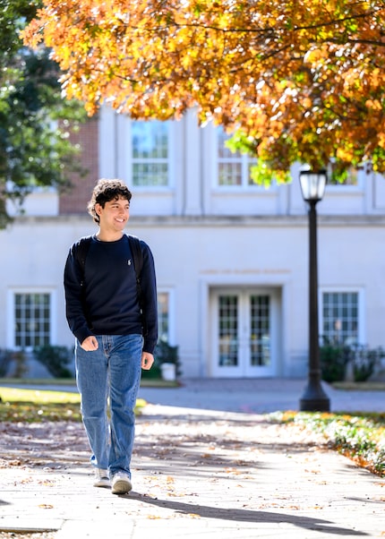 SMU college student walks on a paved pathway on campus.