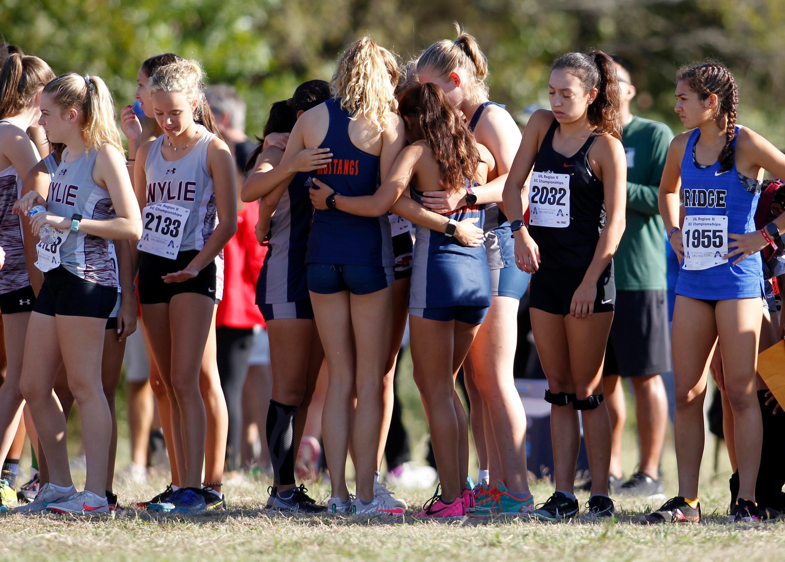 A team of runners pause to pray before the start of the girls race. The Class 6A Region ll...