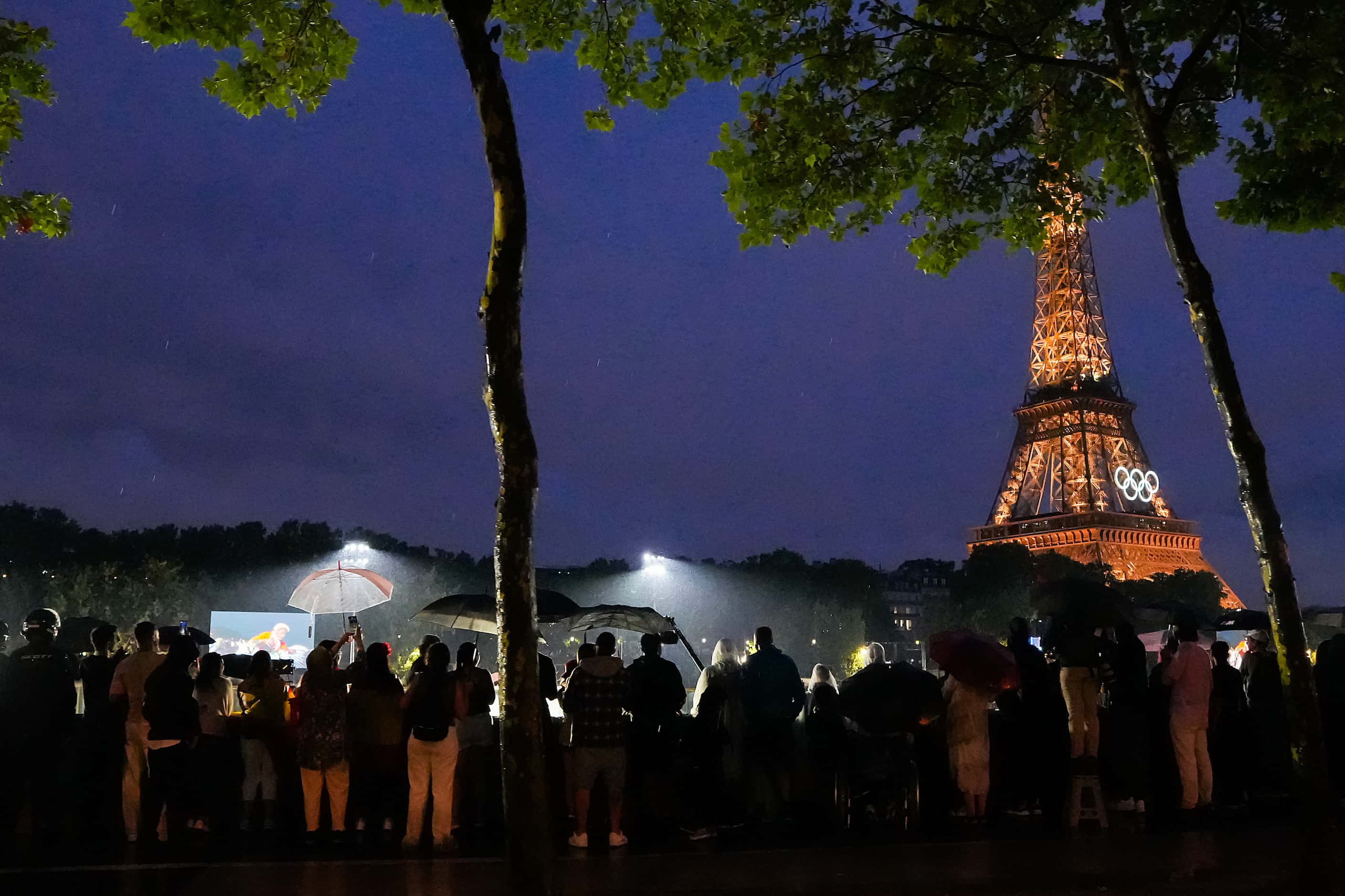 Spectators watch from along the Seine during opening ceremonies for the 2024 Summer Olympics...