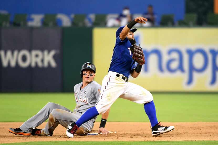 Texas Rangers second baseman Rougned Odor, right, makes an errant throw to first base while...