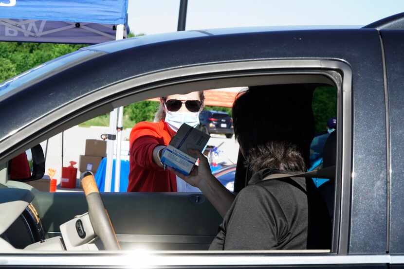 Aimee Rockhill-Carpenter assists someone during a free mask giveaway in the parking lot at...