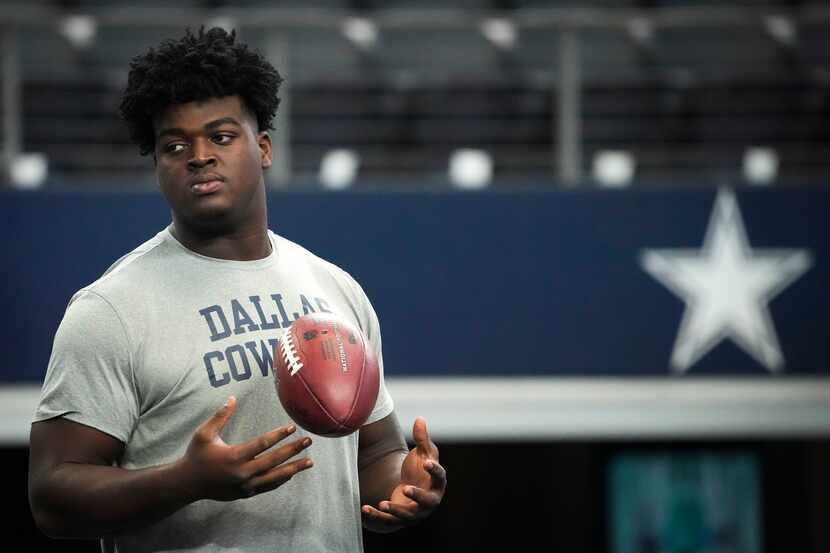 Dallas Cowboys offensive tackle Tyler Smith watches teammates warm up before an NFL...