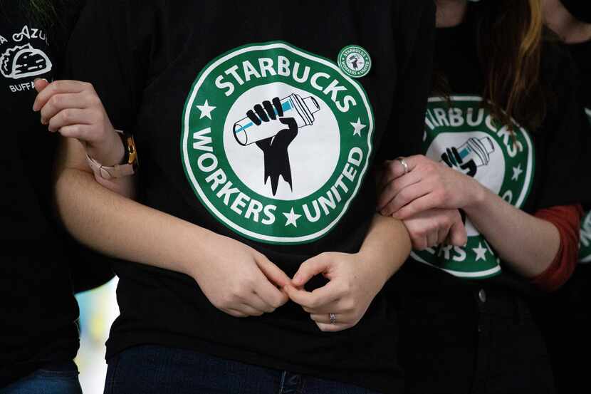 FILE - Starbucks employees and supporters linked arms during a union election watch party...