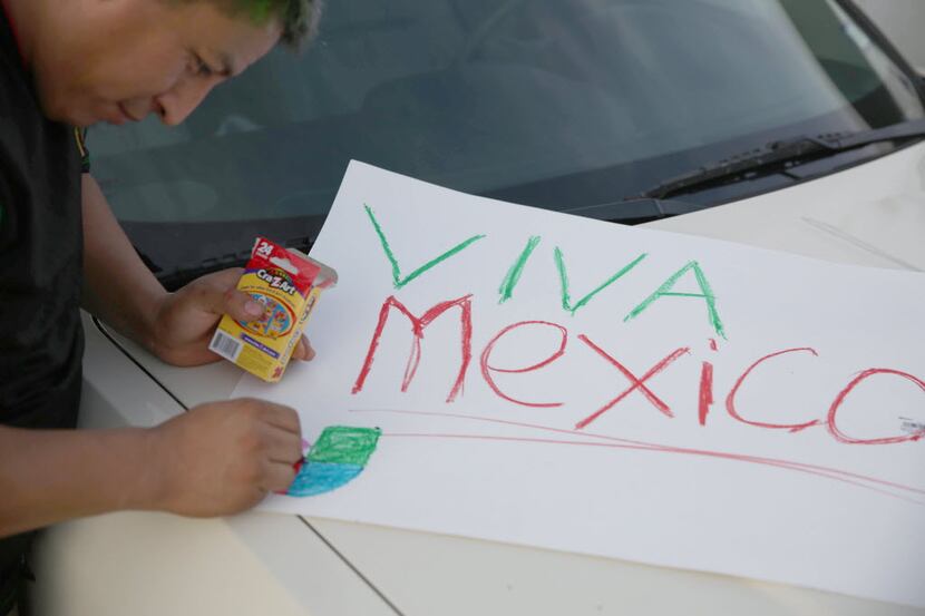 Mexico fan Manuel Francisco, of Denton, Texas, prepares a sign in the parking lot outside...
