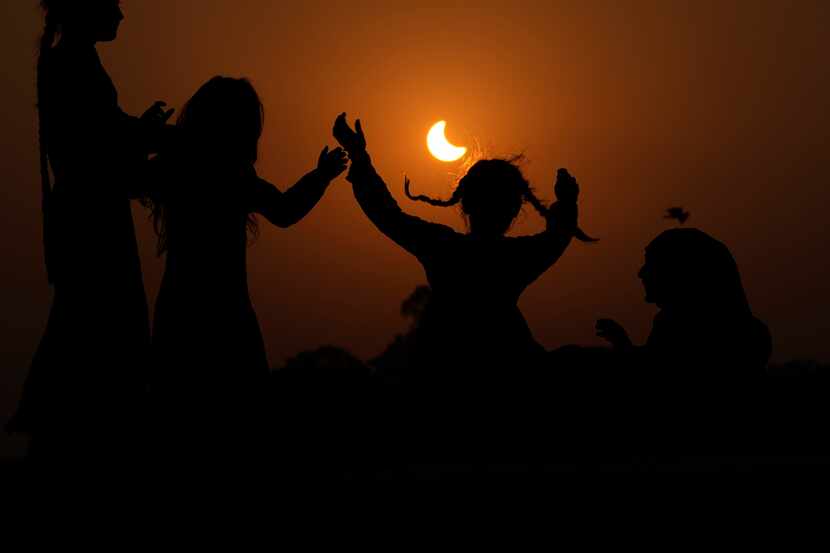 Un eclipse solar parcial es enmarcado por niñas que saltan en un trampolín en las afueras de...