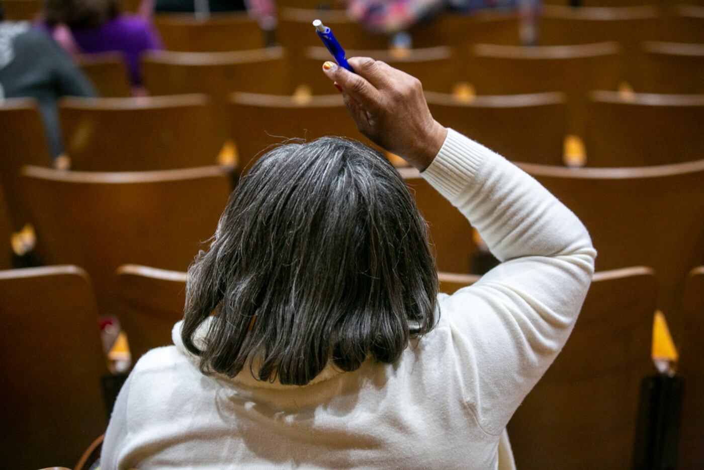 An attendant raises her hand to ask a question during a Dallas Independent School District...