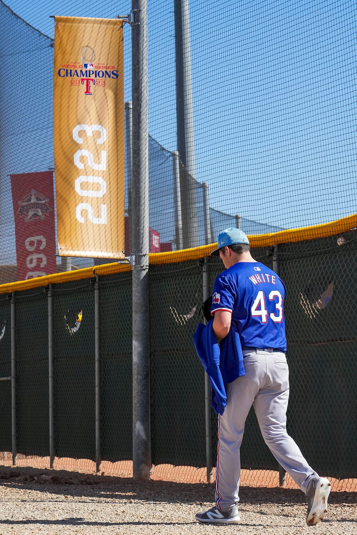 Texas Rangers pitcher Owen White passes a banner commemorating the Rangers 2023 World Series...