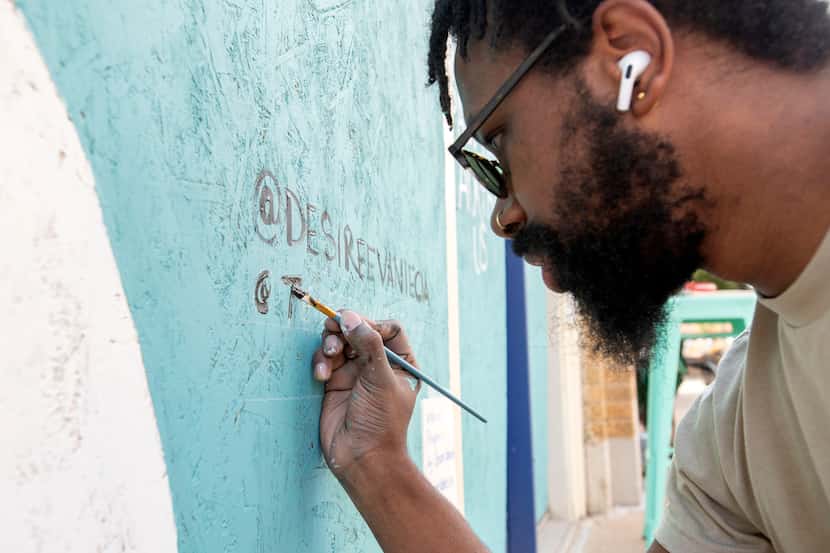 Joeneal Berry signs his name on a mural he painted with Desiree Vaniecia on plywood on...