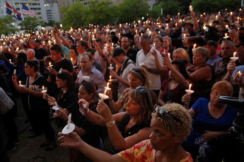 Mourners hold candles during a candlelight vigil hosted by the Dallas Police Association at...