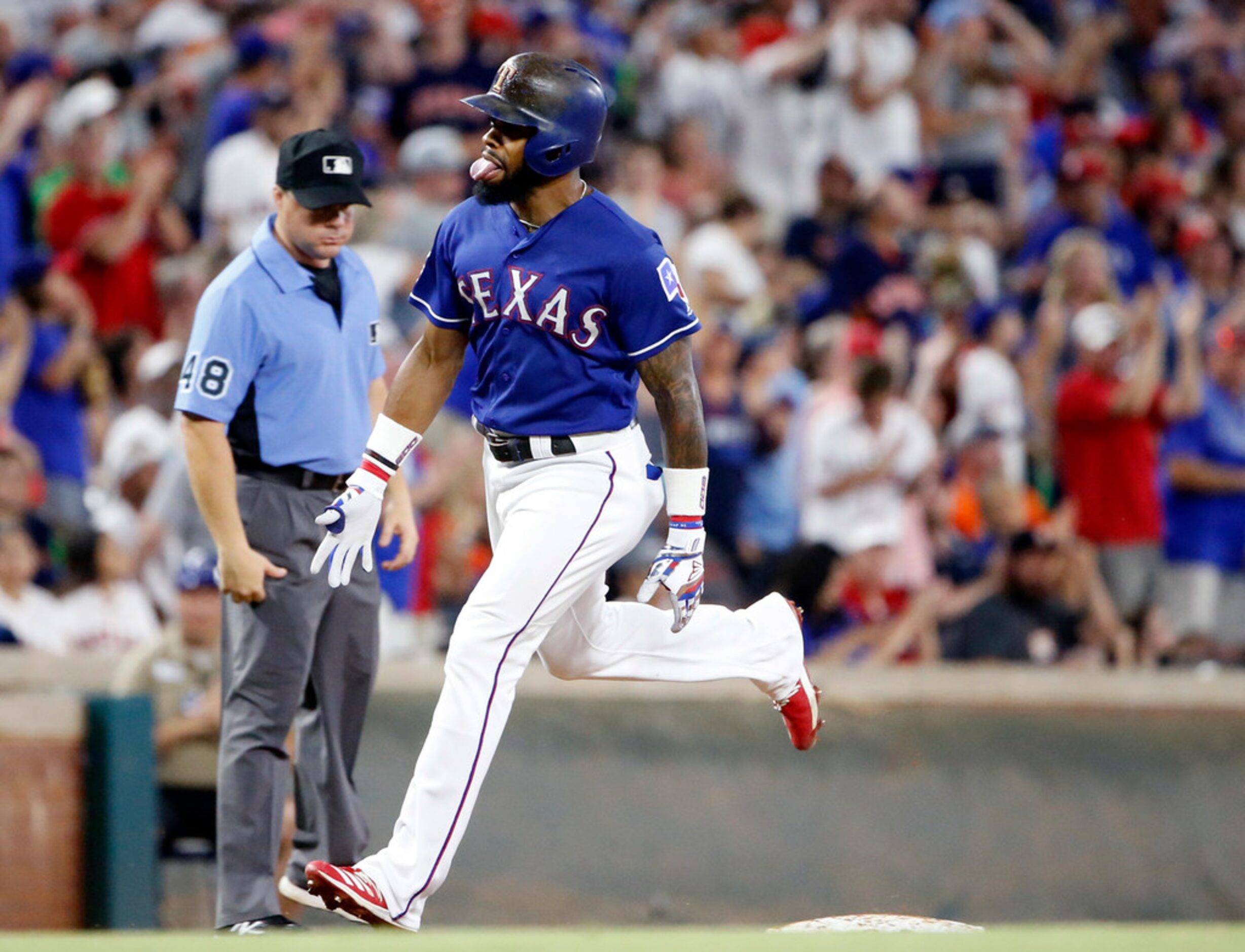 Texas Rangers Delino DeShields sticks out his tongue as he rounds third base after hitting a...