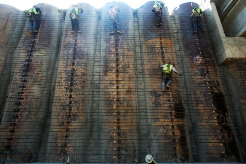 Construction workers added support beams to a wall during construction on Highway 161 in...