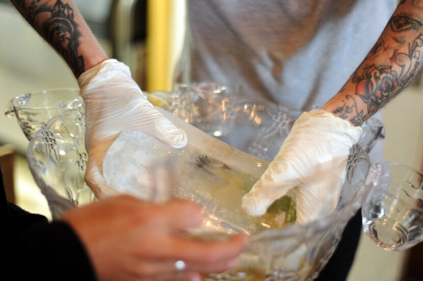 A large block of ice is carefully placed in the punch bowl at Truck Yard in Dallas.