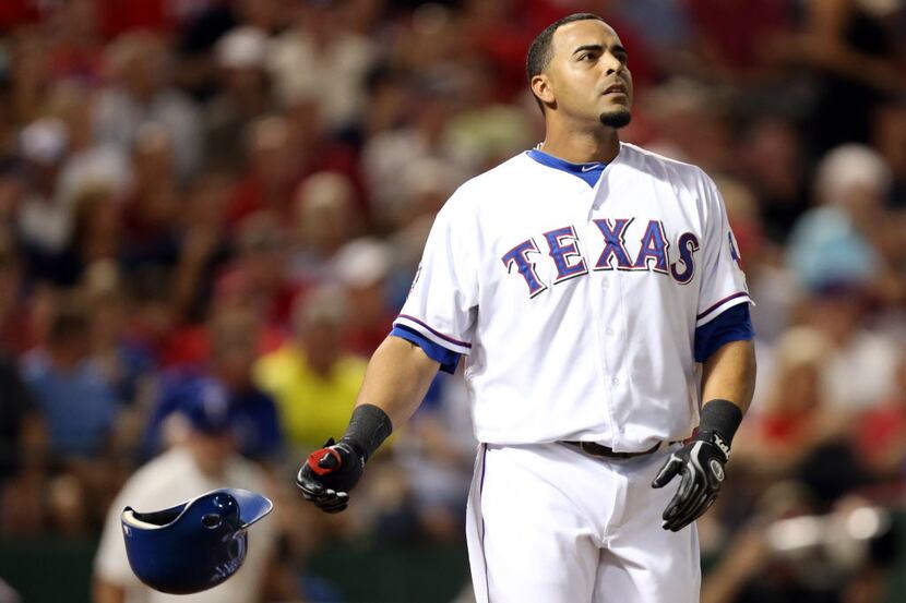 Texas right fielder Nelson Cruz throws his helmet aside after striking out to end the first...