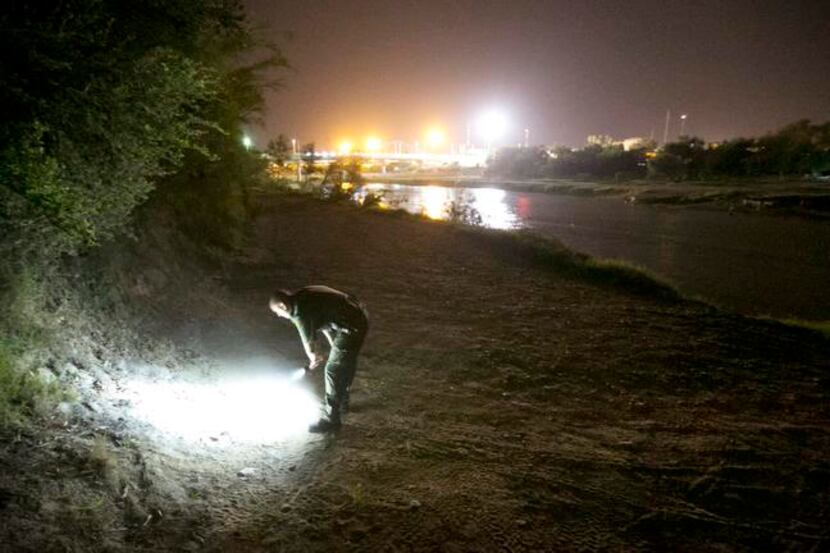 
A Border Patrol agent looks at footprints as he searches the banks of the Rio Grande in...