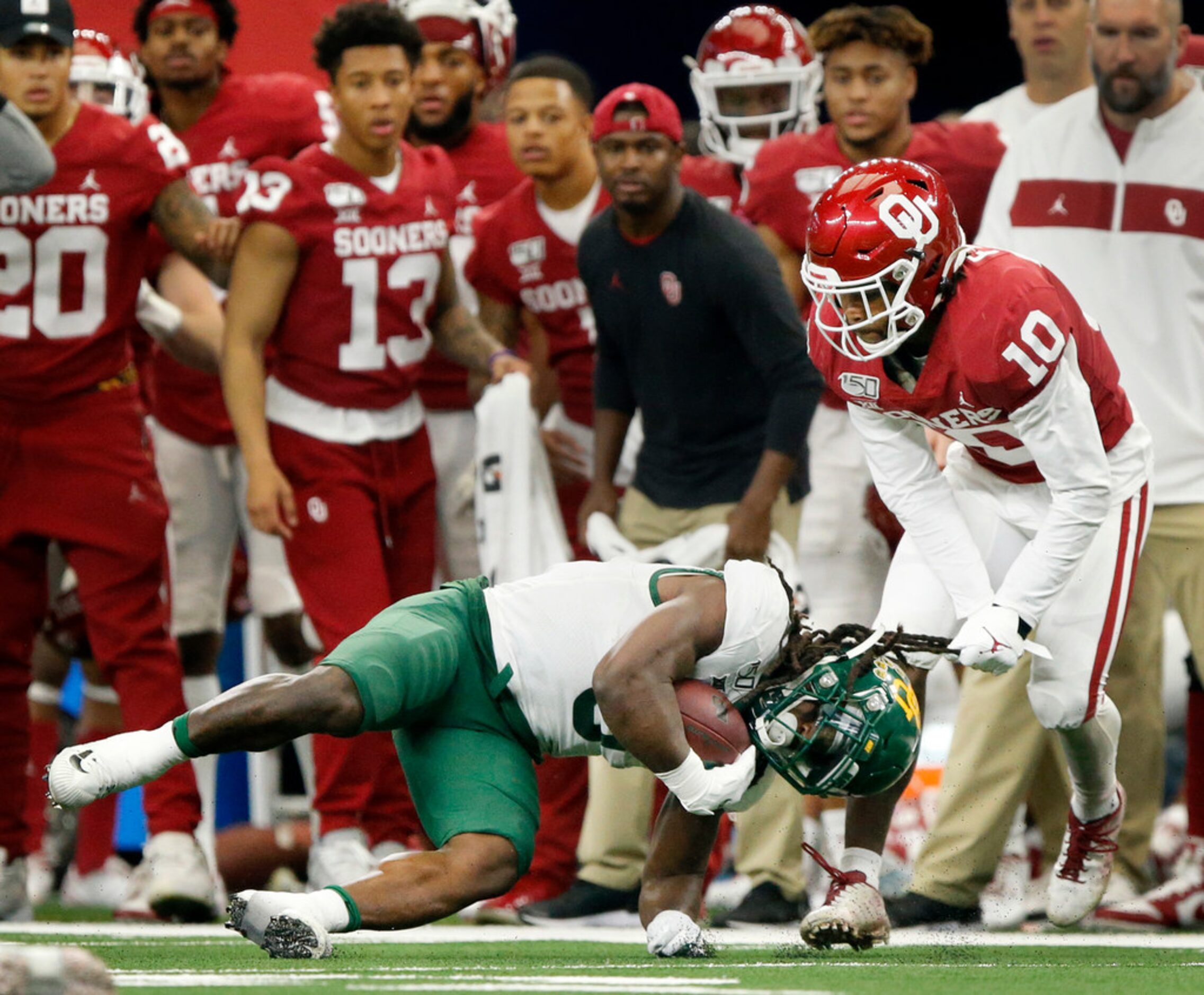 Baylor Bears running back JaMycal Hasty (6) is pulled down by his hair by Oklahoma Sooners...