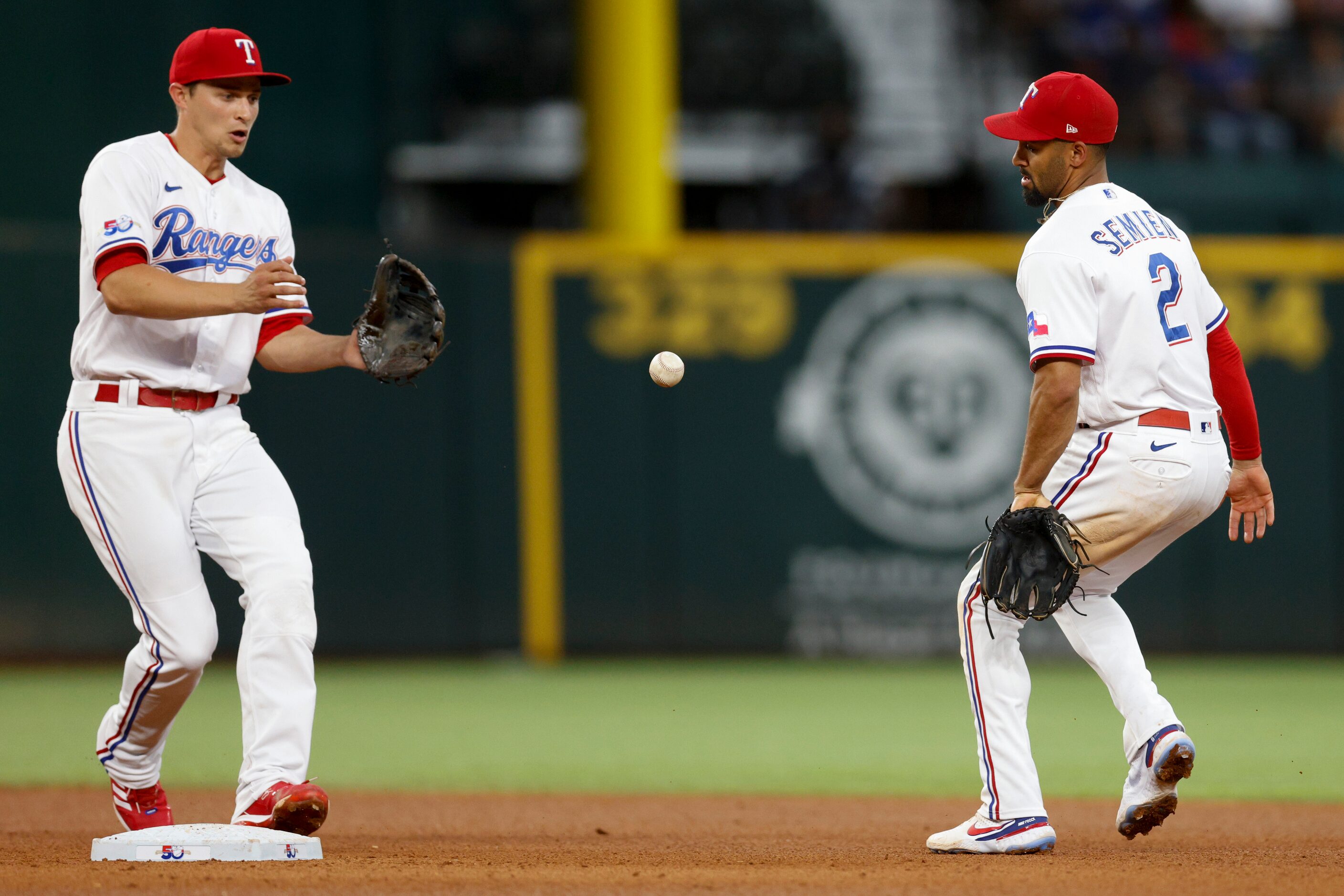 Texas Rangers second baseman Marcus Semien (2) flips the ball to shortstop Corey Seager (5)...