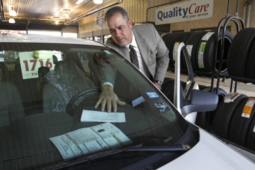 Pre-owned manager Rick Galvan slips a "check" onto the dashboard of a car being serviced at ...