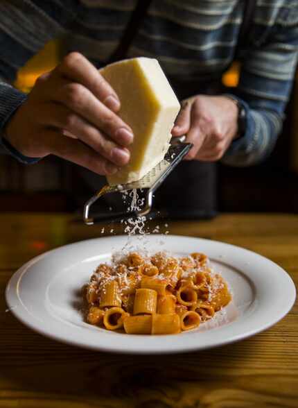 Chef Julian Barsotti grates pecorino romana cheese over Mezze all'Amatriciana pasta. He...