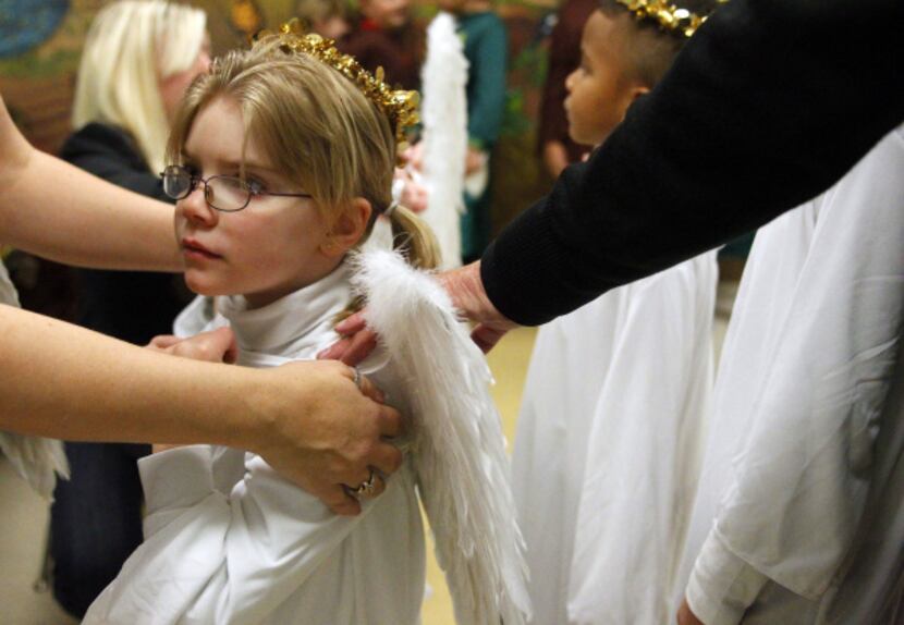 Six-year-old Emily Bone-Richardson is fitted with angel wings for the Christmas pageant at...