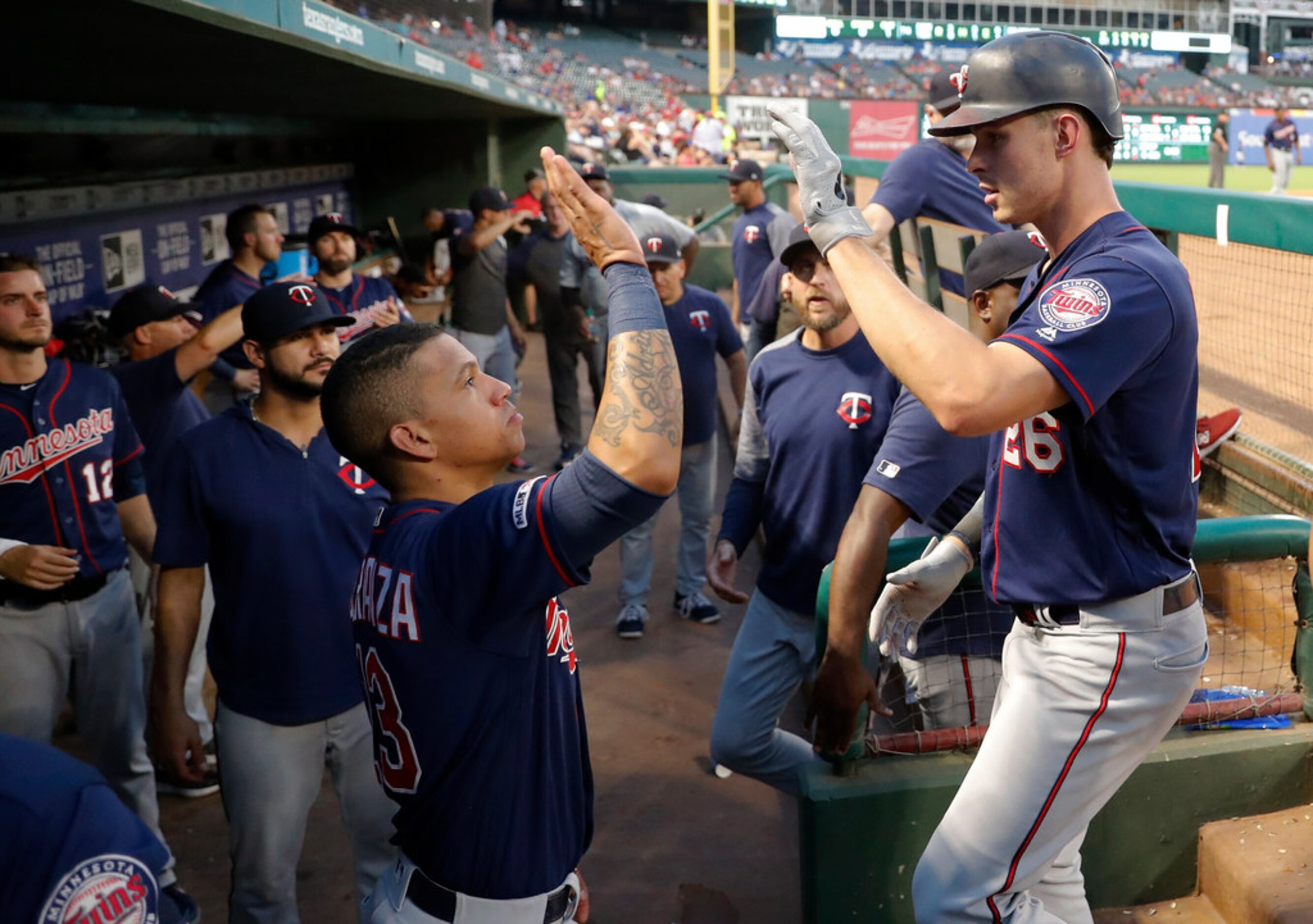 Minnesota Twins' Max Kepler, right, is greeted at the dugout by Ehire Adrianza and others...