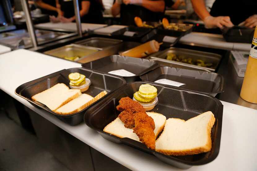 The kitchen makes and assembles orders during the opening of Dave’s Hot Chicken in Plano on...