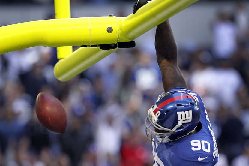 New York Giants defensive end Jason Pierre-Paul (90) dunks the ball over the goal post after...