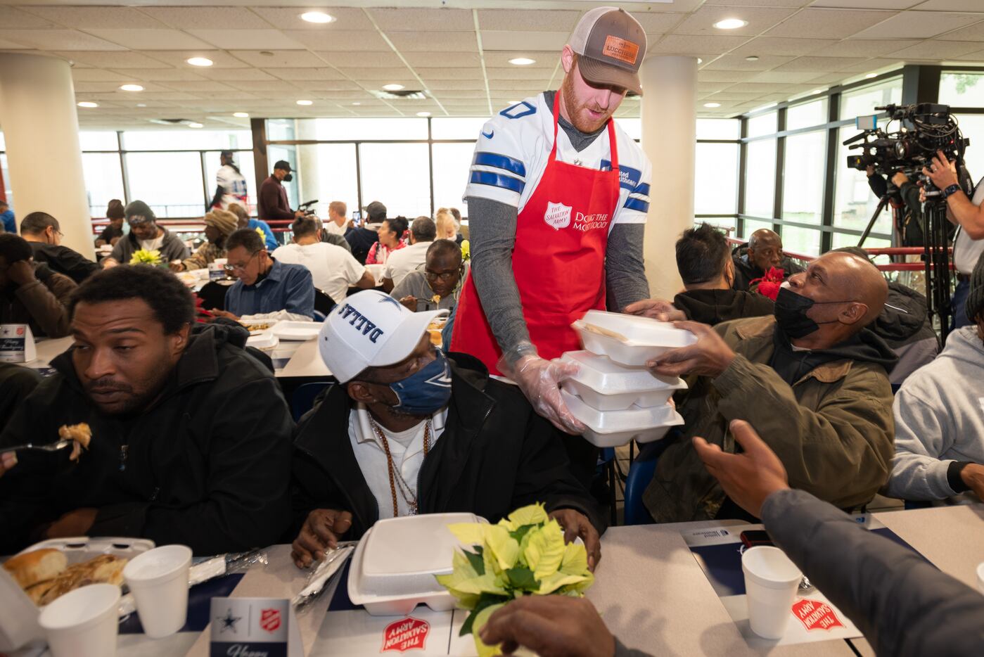 Dallas Cowboys backup quarterback Cooper Rush hands Thanksgiving meals to men and women at...