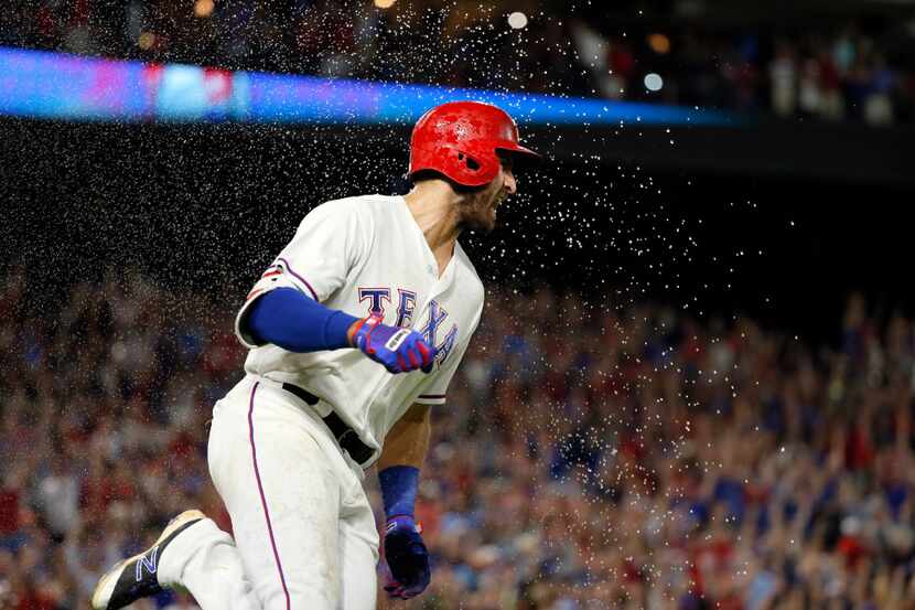 Texas Rangers' Joey Gallo runs through a spray of water tossed by Keone Kela, not pictured,...