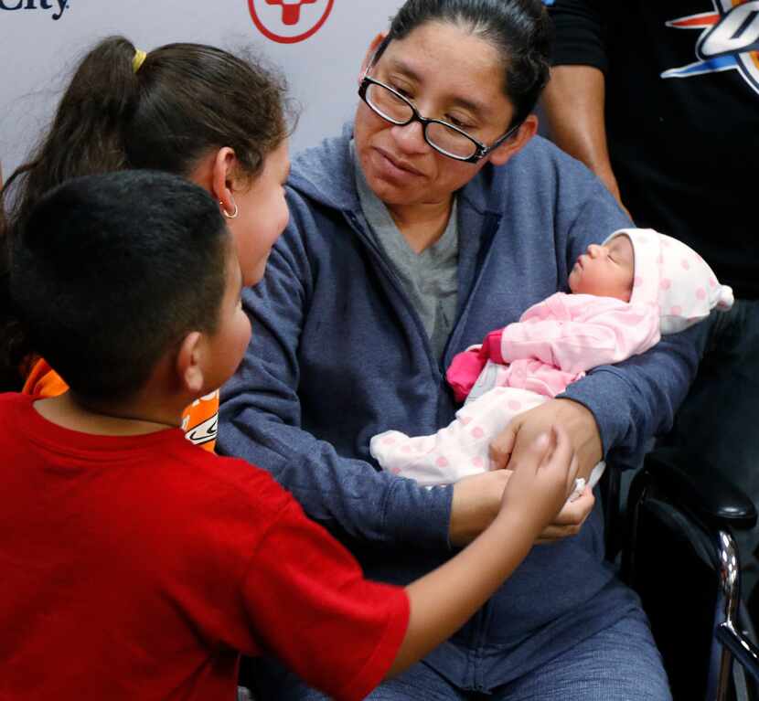 Nora Uribe holds her newborn baby daughter, Ximena, with her children, Antonio, 4, and...