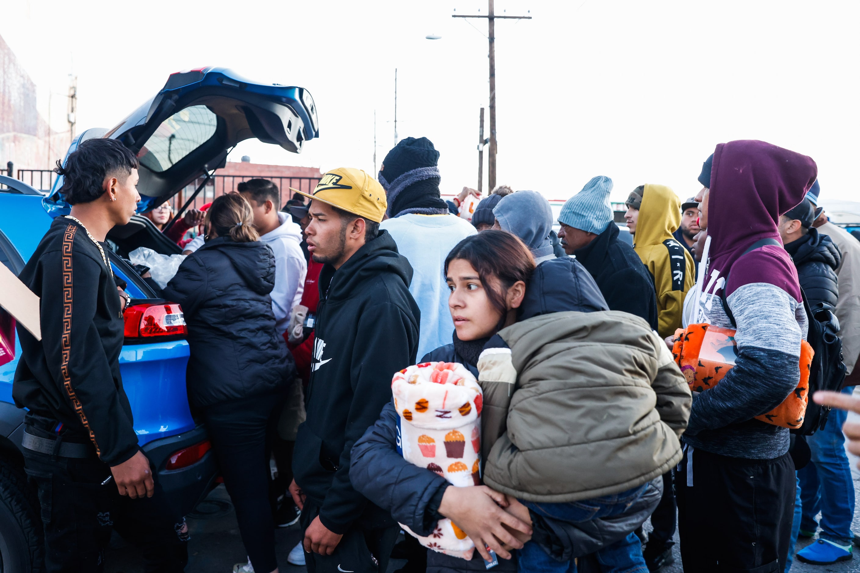 Migrants outside the Centro Pastoral Sagrado Corazon receive aid from local people in El...