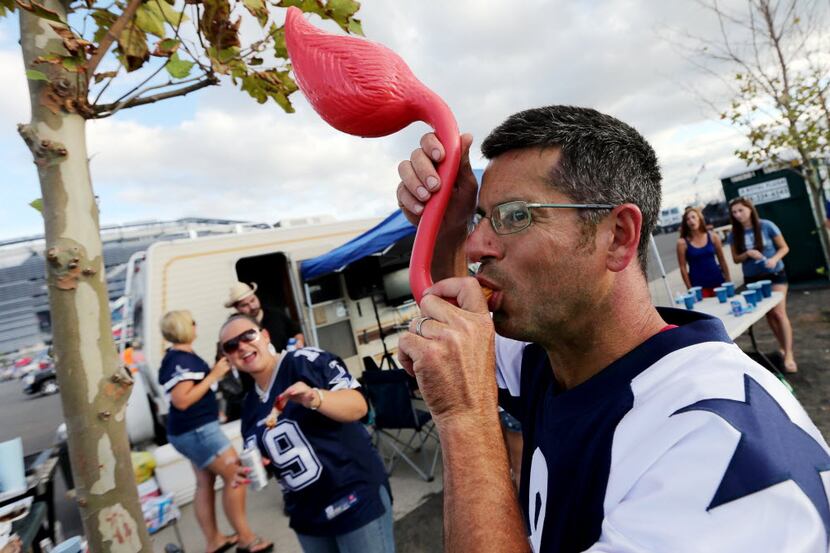 Cowboys fan Jeff Weiss drinks beer through a hollowed out pink flamingo in the parking lot...