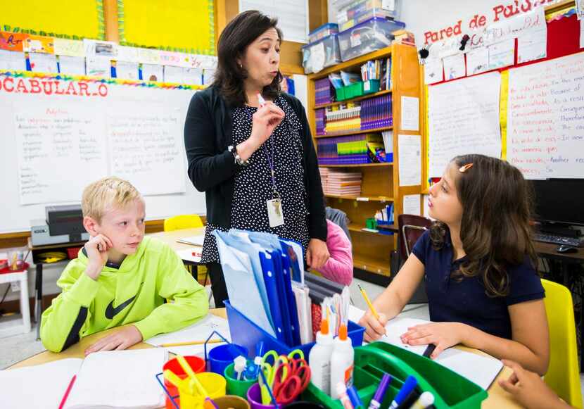 
Third-grade teacher Irma De La Guardia helps Adeline VanderMeer, 9 (right) and Matthew...