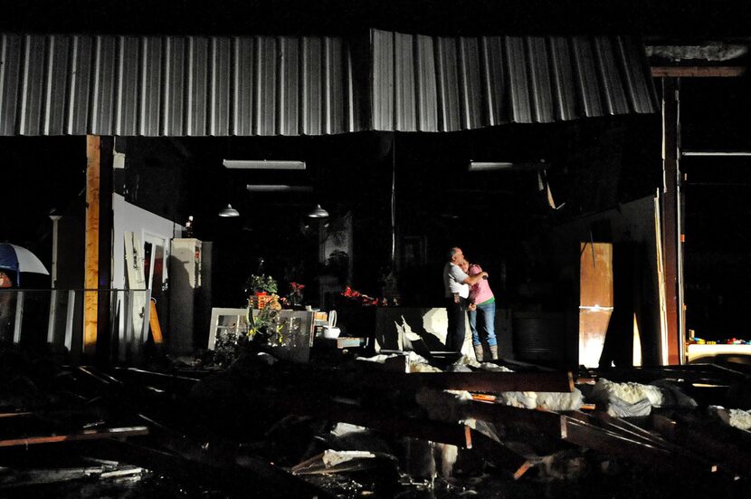 Jeff and Melissa McKenzie embrace in the ruins of their florist and gift shop store in...