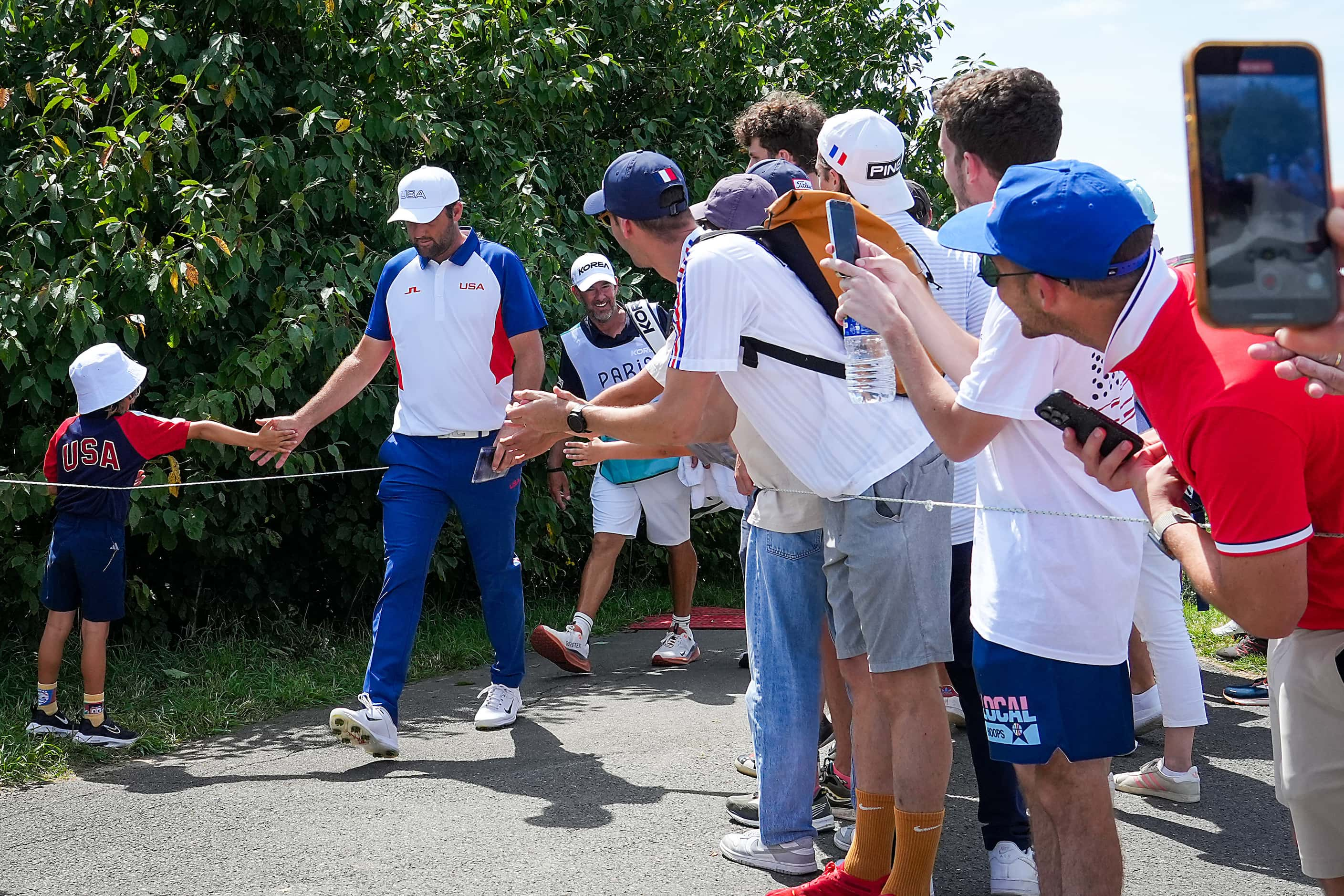 Gold medalist Scottie Scheffler of the United States reaches out to a young fan while...